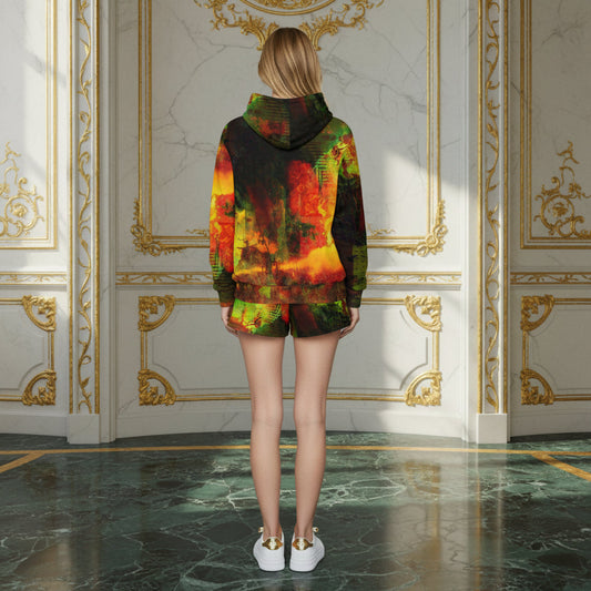 A woman stands with her back to the camera wearing a matching hooded sweatshirt and shorts set with a vibrant, multicolored abstract print featuring red, orange, yellow, and green. She is photographed in an elegant room with white walls decorated with gold paneling and a green marble floor.