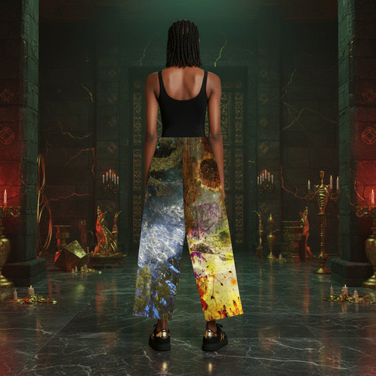 A person stands with their back to the camera in a dark, gothic hall with candelabras and stone pillars, wearing wide-leg cropped pants with a split design: one leg is blue-gray with a textured pattern, and the other leg features a yellow, orange, and brown abstract print.