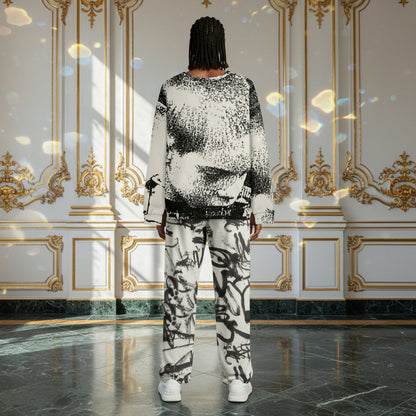 A model viewed from behind wearing a matching black and white abstract patterned sweatshirt and trousers set, standing in a grand room with gold-trimmed white walls and a polished marble floor.