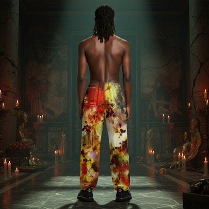 A shirtless man with dreadlocks stands with his back to the camera in a dark, candle-lit hall, wearing loose pants with a vivid abstract print in red, yellow, orange, and cream.