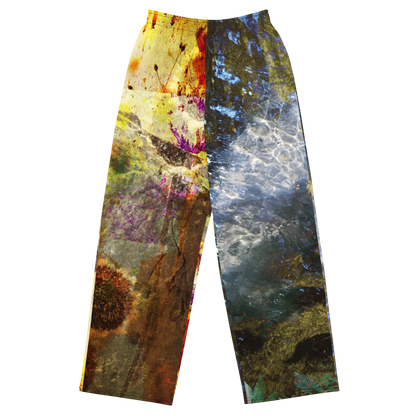 A pair of wide-leg pants featuring a split abstract design: one leg has a yellow, brown, and purple paint-splatter pattern, while the other leg has a blue, gray, and white water-like pattern, shown against a plain white background.