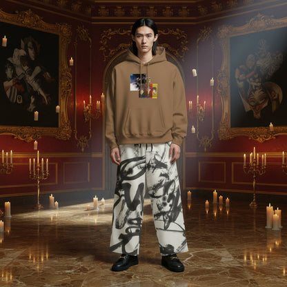 A model stands in a grand, candle-lit room wearing a brown hoodie with a graphic chest print and wide-leg white pants with black abstract brushstrokes.