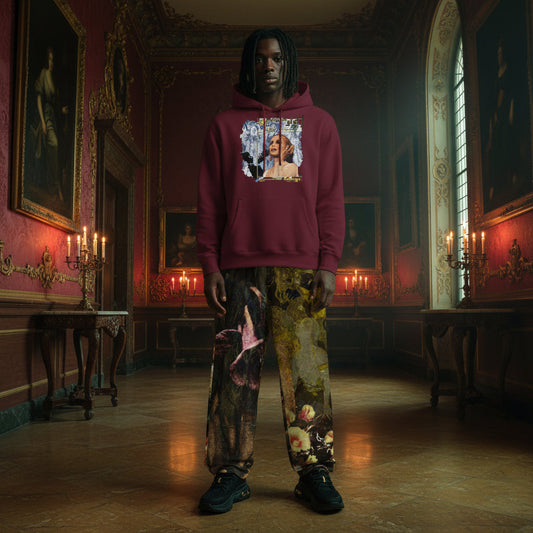 A person stands in a grand, candle-lit historical room wearing a burgundy hoodie with a graphic print on the chest and matching patterned pants featuring classical artwork.
