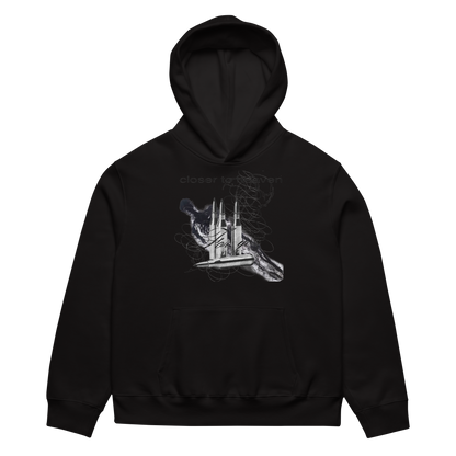 A black pullover hoodie with a white and gray graphic print on the chest depicting a hand holding a ship's wheel, with the faint text 'closer than death' above it, shown against a plain white background.
